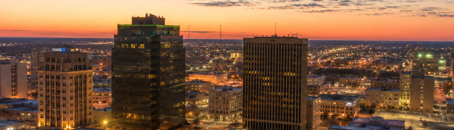 Downtown Midland, Texas, at sunset, with city lights stretching to a flat horizon